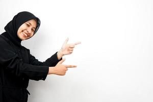 bela jovem asiática muçulmana com as mãos apontando para o espaço vazio, apresentando algo, isolado no fundo branco foto