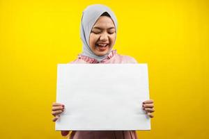 muito jovem mulher muçulmana alegre segurando uma faixa vazia em branco, cartaz, quadro branco, placa de sinalização em branco, quadro de propaganda branco, apresentando algo no espaço da cópia, promoção foto