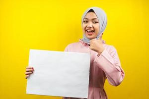 muito jovem mulher muçulmana alegre segurando uma faixa vazia em branco, cartaz, quadro branco, placa de sinalização em branco, quadro de propaganda branco, apresentando algo no espaço da cópia, promoção foto