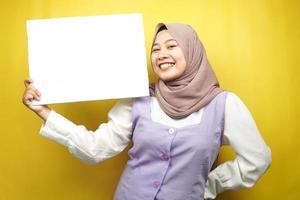 muito jovem mulher muçulmana alegre segurando uma faixa vazia em branco, cartaz, quadro branco, placa de sinalização em branco, quadro de propaganda branco, apresentando algo no espaço da cópia, promoção foto