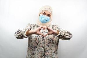 mulheres muçulmanas usando máscaras médicas com as mãos do amor, movimento antivírus corona, movimento anti covid-19, movimento de saúde usando máscaras, isolado no fundo branco foto