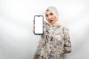 bela jovem muçulmana asiática chocada, surpresa, expressão uau, mão segurando o smartphone com tela branca ou em branco, promovendo app, promovendo produto, apresentando algo, isolado