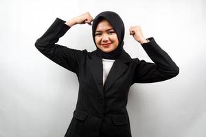 Mulher de negócios jovem muçulmana asiática bonita com músculos levantados, braços de sinal de força, isolado no fundo branco foto
