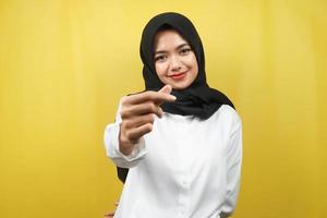 bela jovem muçulmana asiática sorrindo, com sinal de amor coreano, mão perto da câmera, isolado no fundo amarelo foto