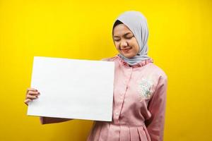 muito jovem mulher muçulmana alegre segurando uma faixa vazia em branco, cartaz, quadro branco, placa de sinalização em branco, quadro de propaganda branco, apresentando algo no espaço da cópia, promoção foto