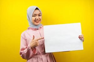 muito jovem mulher muçulmana alegre segurando uma faixa vazia em branco, cartaz, quadro branco, placa de sinalização em branco, quadro de propaganda branco, apresentando algo no espaço da cópia, promoção foto