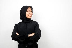 linda jovem muçulmana asiática confiante e alegre, olhando o espaço vazio, apresentando algo, isolado no fundo branco foto