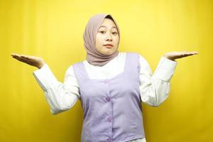 bela jovem muçulmana asiática com expressão de não sei sinal, isolada em fundo amarelo