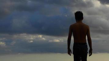 vista traseira de um homem sem camisa contra um fundo de céu nebuloso foto