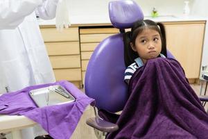jovem sentindo medo quando o dentista limpa os dentes na clínica odontológica foto