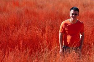 retrato de homem de camisa laranja em pé no campo de prado laranja foto