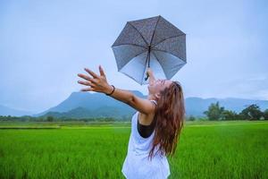 mulheres asiáticas viajam relaxam no feriado. a garota sorriu feliz e aproveitou a chuva que estava caindo. viajando no interior, campos de arroz verdes, viajar na Tailândia. foto