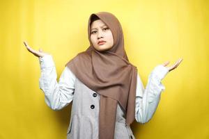 bela jovem muçulmana asiática com expressão de não sei sinal, isolada em fundo amarelo