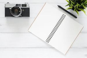 espaço de trabalho mínimo - foto criativa plana da mesa do espaço de trabalho. mesa de escritório branco mesa de madeira fundo com mock up notebooks e câmera retro. vista superior com cópia espaço, fotografia plana lay