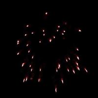 fogos de artifício vermelhos escuros explodem no ar iluminam o céu com uma exibição deslumbrante e festivais de fogos de artifício coloridos no preto. foto