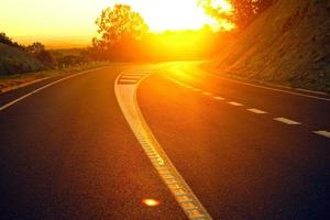 laranja do sol na estrada trilha bela estrada virando nas colinas e estrada de montanha estrada de pastagem à noite em. foto