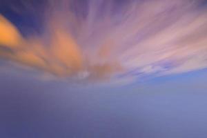 pôr do sol e nuvem laranja e céu azul do amanhecer com efeito de movimento de linhas horizontais de nuvem no fundo do sol. foto