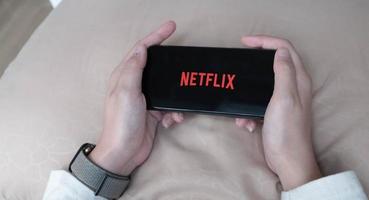 mão de mulher segurando um telefone inteligente com o logotipo da Netflix no apple iphone xs. netflix é um provedor global de streaming de filmes e séries de TV. foto