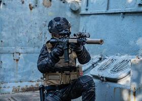 soldado moderno em uniforme multicam preto com rifle, meio urbano