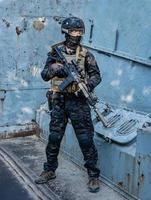 soldado moderno em uniforme multicam preto com rifle, meio urbano