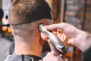 barbeiro raspa a cabeça do cliente com um aparador elétrico