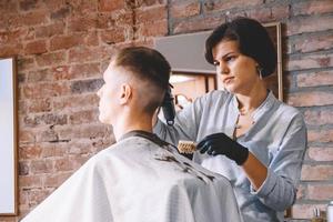 cabeleireiro de mulher bonita raspa a cabeça da cliente com um aparador elétrico na barbearia. conceito de publicidade e barbearia foto