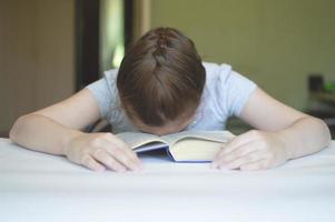 criança lendo um livro na mesa foto