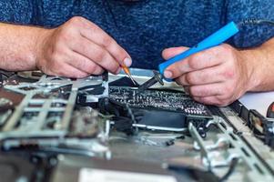 um homem conserta um computador, solda uma placa, conserta eletrônicos e tecnologias modernas foto