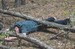 um corpo na floresta. um homem morto com uma camiseta e calças azuis está preso por uma árvore caída. conceito de acidentes na floresta. foto
