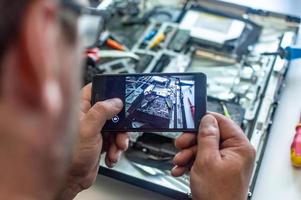 um homem conserta um computador, solda uma placa, conserta eletrônicos e tecnologias modernas foto