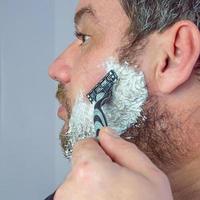 um homem com uma barba grisalha faz a barba foto