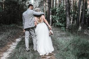 a noiva e o noivo se abraçam na floresta no dia do casamento. cerimônia de casamento. foco seletivo. grão de filme. foto