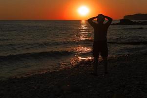 a silhueta de um homem no contexto de um pôr do sol à beira-mar. solidão.