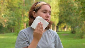 uma adolescente com um corte de cabelo curto enxuga o rosto com um guardanapo de suor no calor depois de comer enxuga os lábios