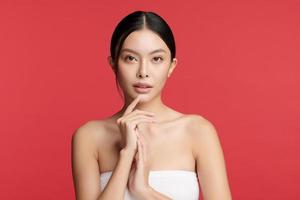 bela jovem asiática com pele limpa, fresca sobre fundo vermelho, cuidados faciais, tratamento facial, cosmetologia, beleza e spa, retrato de mulheres asiáticas. foto