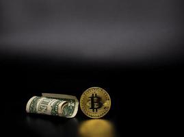 ouro bitcoin e notas de dólar em fundo preto. foto