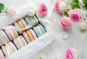 Macaroons coloridos em uma caixa de presente e rosas foto