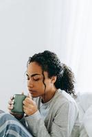 mulher africana a sonhar a beber café foto