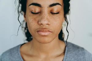 mulher negra posando com os olhos fechados enquanto passa um tempo em casa