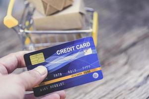 cartão de crédito de pagamento online e caixas de encomendas no carrinho de compras - compra de tecnologia online e conceito de pagamento com cartão de crédito foto