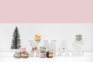 macaroons de sobremesa rench ou macarons em fundo branco e rosa de Natal com inscrição Natal. conceito de receita de comida. copie o espaço. foto