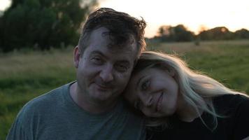 pai e filha loira adulta estão sentados em um abraço no contexto da natureza de outono ao pôr do sol
