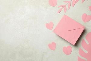 envelope, folhas de papel e corações em plano de fundo texturizado branco foto