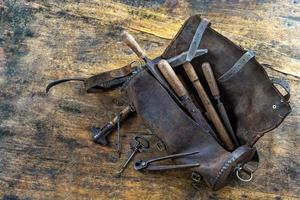 conjunto de ferramentas em bolsa de couro velha no chão de madeira de omd foto