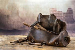 conjunto de ferramentas em bolsa de couro velha no chão de madeira de omd foto