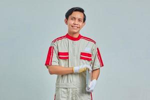 retrato de um homem bonito e sorridente mecânico vestindo uniforme segurando o laptop sobre fundo cinza foto