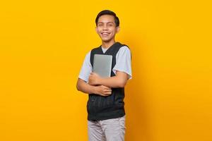 retrato de homem asiático alegre trazendo laptop sobre fundo amarelo