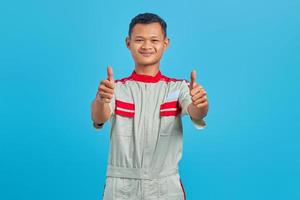 retrato de um jovem mecânico asiático sorridente, mostrando o polegar para cima gesto isolado sobre fundo azul