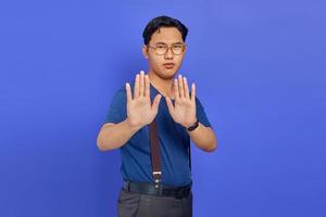 retrato de homem bonito bravo fazendo gesto de parada com as palmas das mãos no fundo roxo foto
