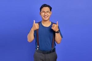 retrato de querido homem asiático mostrando os polegares para cima ou sinal de aprovação isolado no fundo roxo foto